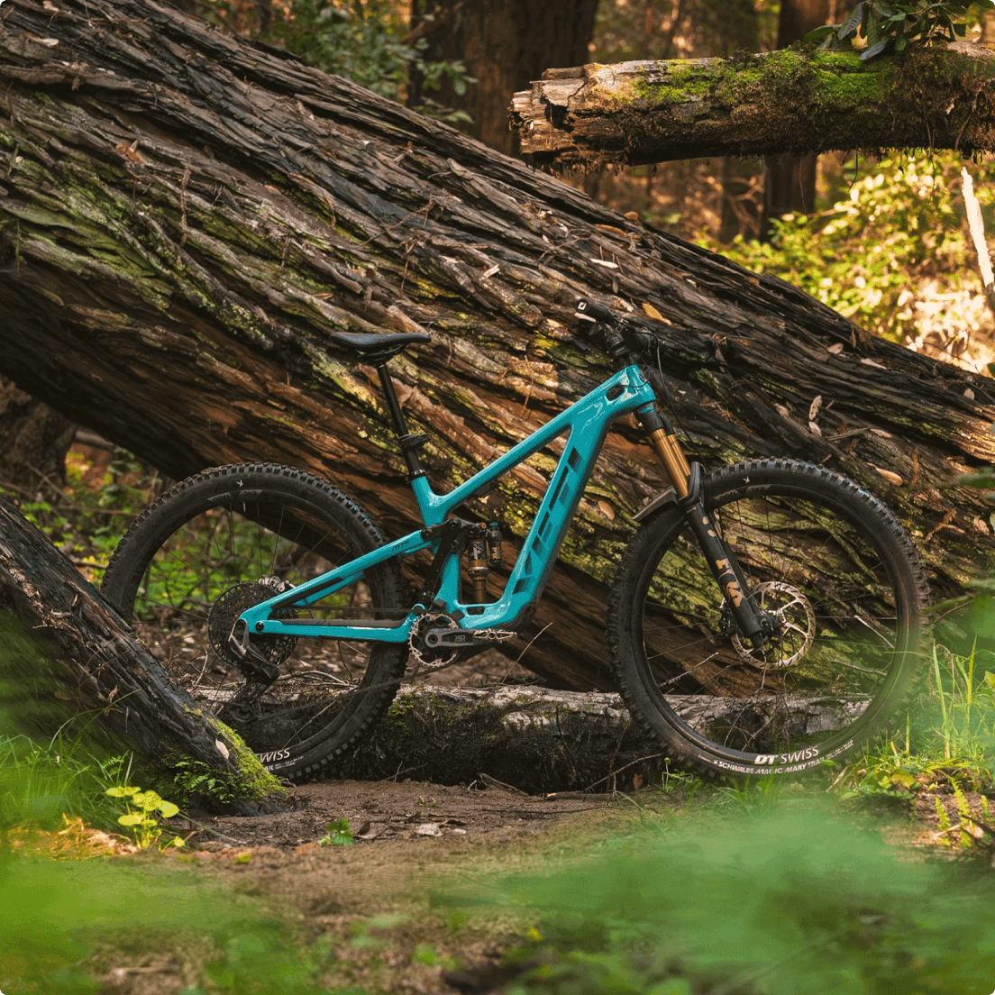 Bicicleta de montaña de doble suspensión de color turquesa de Yeti Cycles con ruedas DT Swiss en un sendero forestal de tierra